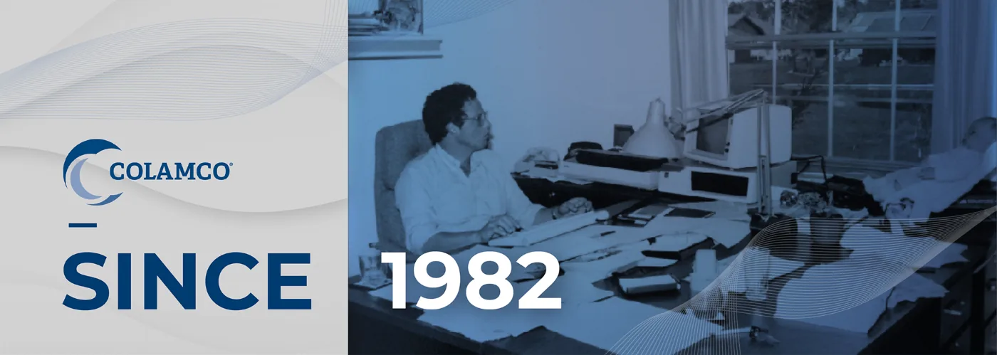COLAMCO, since 1982: an archival photograph of a person working at a desk with early-1980s computer and printing equipment.